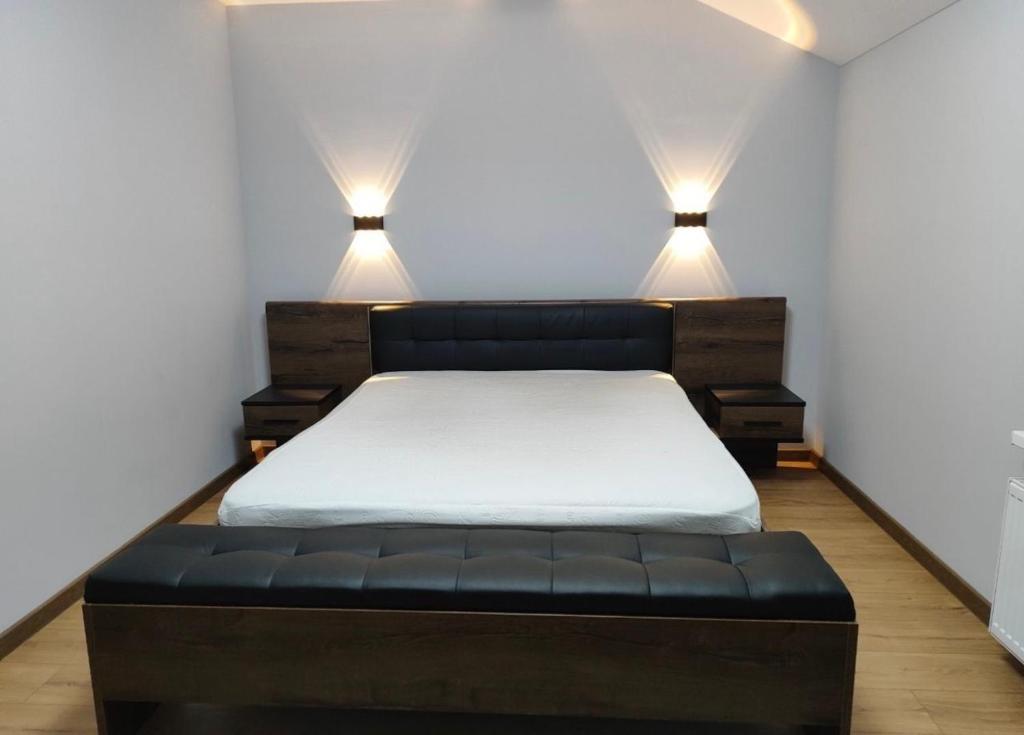 a bedroom with a bed with two lights on the wall at Дім весняний in Sheremetka
