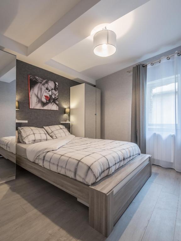 a bedroom with a large bed and a painting on the wall at Appart Hôtel Bourgoin in Bourgoin
