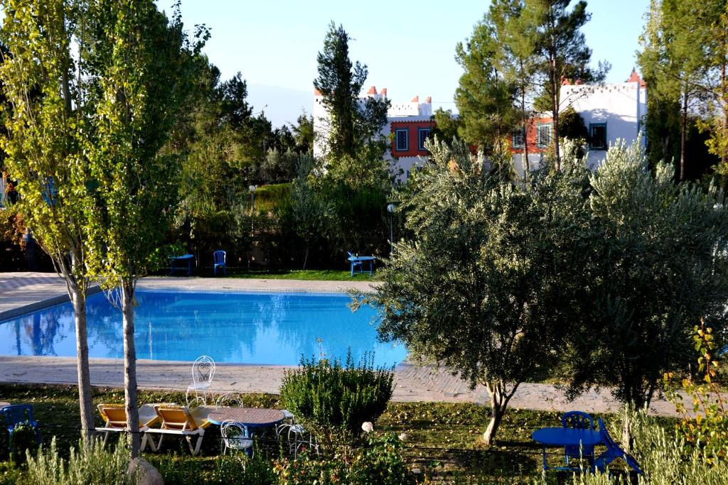 uma piscina num quintal com cadeiras e árvores em Riad Mimouna De Timnay em Aguelmous