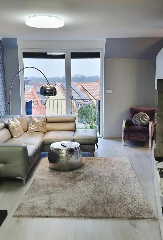 a living room with a couch and a large window at Sunshine Residence Silver Apartment in Hévíz