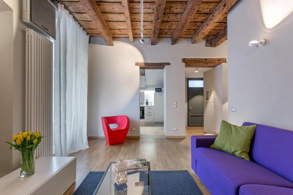 un soggiorno con divano viola e sedia rossa di La Cortevecchia 2.0 a Bergamo