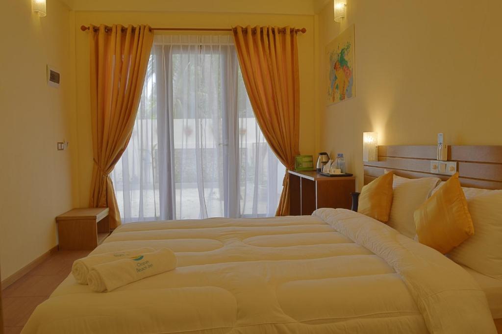 a large bed in a bedroom with a large window at Ocean Beach Inn - Maldives in Hangnaameedhoo