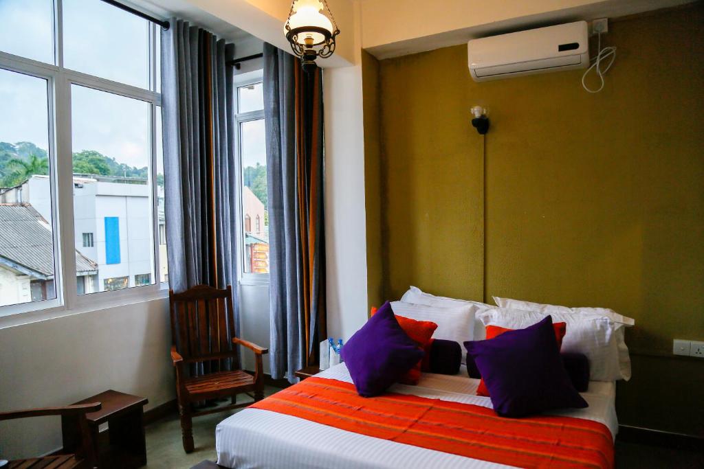 Dumbara Peak Residence في كاندي: غرفة نوم مع سرير مع الوسائد الملونة والنافذة