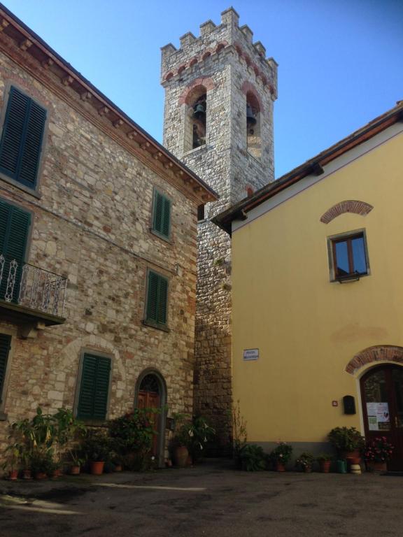 an old stone building with a tower in the background at Dolcevita Chianti Apartments in Radda in Chianti
