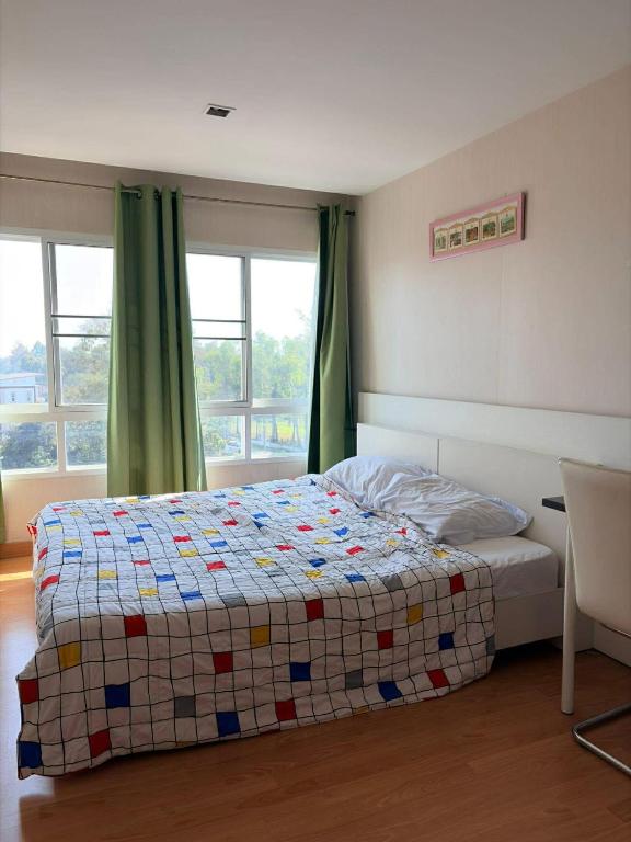 a bedroom with a bed with a quilt on it at Comfort Big condo in Chiang Mai