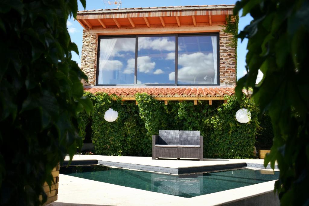 a chair sits in front of a building with ivy at Casa Rural El Bornizo con psicina jacuzzi climatizado barbacoa y jardín en Salamanca in Pastores