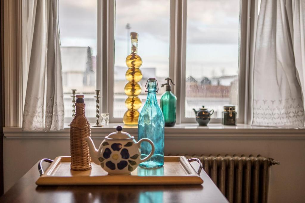 a table with bottles and a tea pot and a window at Merkigil Gisting in Eyrarbakki