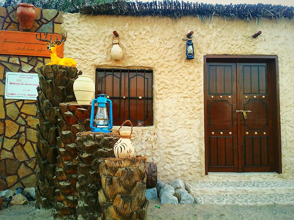 a building with two doors and a stone wall at Al Reem Desert Camp in Jalan Bani Buhassan