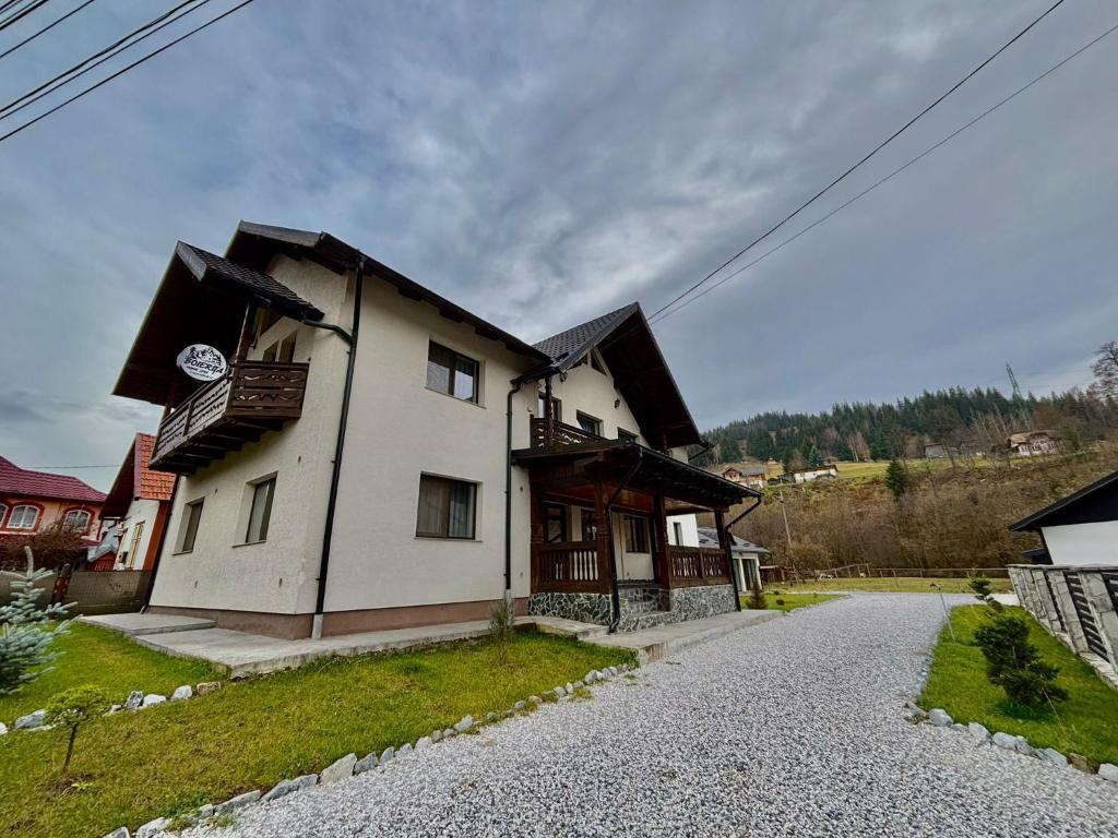 a large white house on a gravel road at Boierița Home Stay in Fundu Moldovei