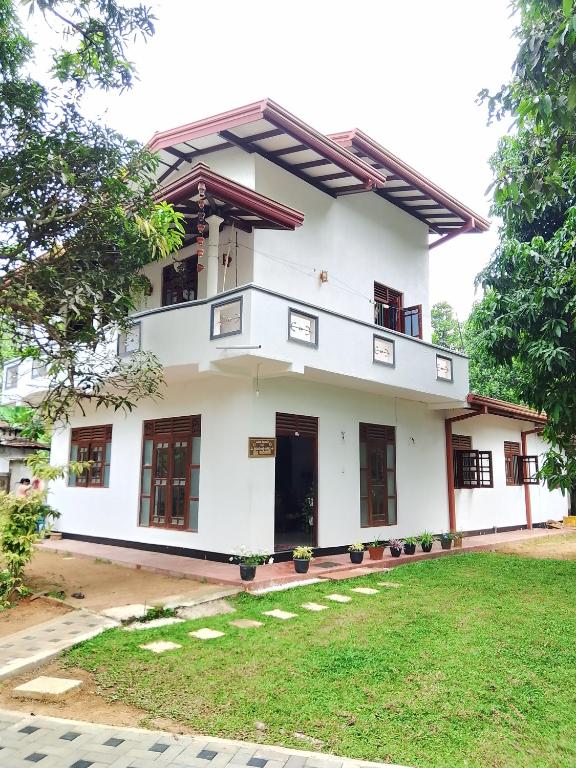 a white building with windows and a yard at Sajini Villa in Weligama