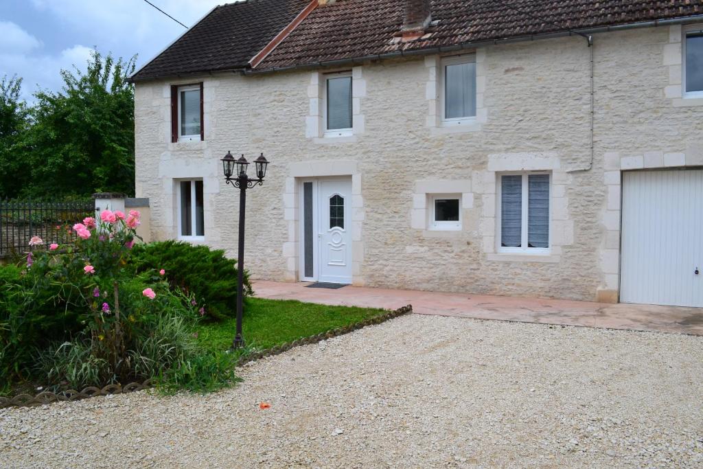 a brick house with a white door and a driveway at La Villa de Jeanne in Les Riceys
