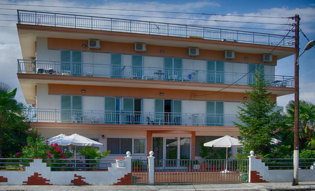 a large building with tables and umbrellas in front of it at Galini Apartments in Olympic Beach