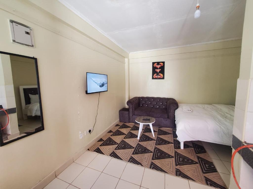 a bedroom with a couch and a bed and a mirror at Nimmoh home in Rungiri