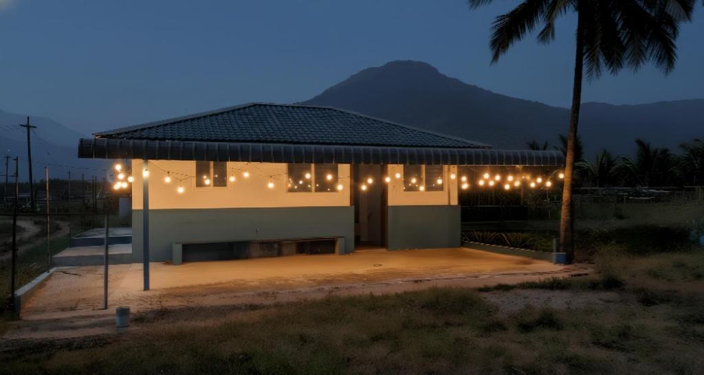 a building with lights on it with a palm tree at Thulir Farm Stay Near Isha Yoga Adiyogi in Coimbatore