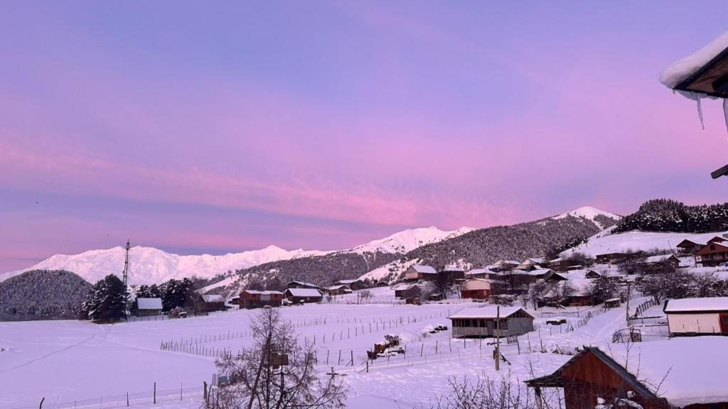 a village covered in snow with mountains in the background at Tusheti Winter Home in Omalo