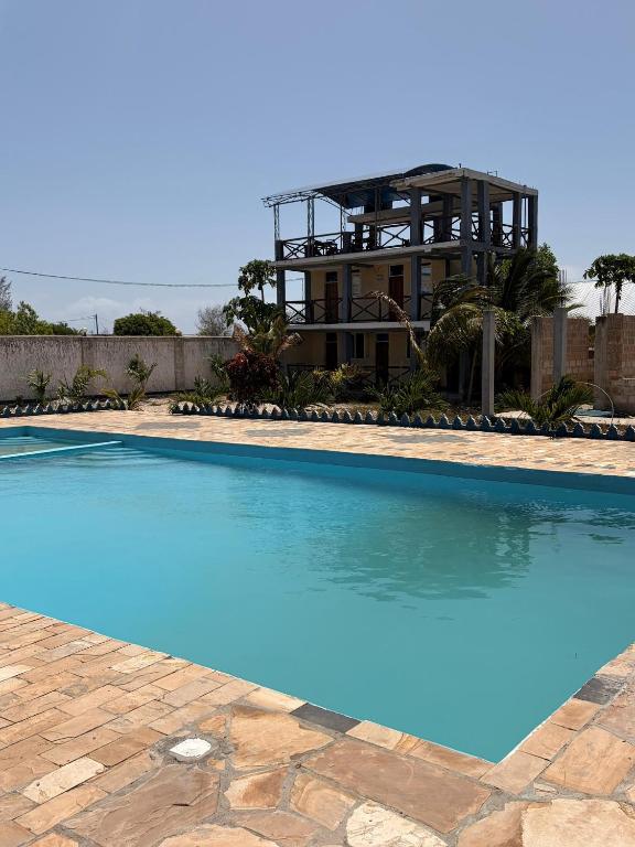 a large swimming pool with a house in the background at Karafuu Nyama Choma Lodge in Bwejuu