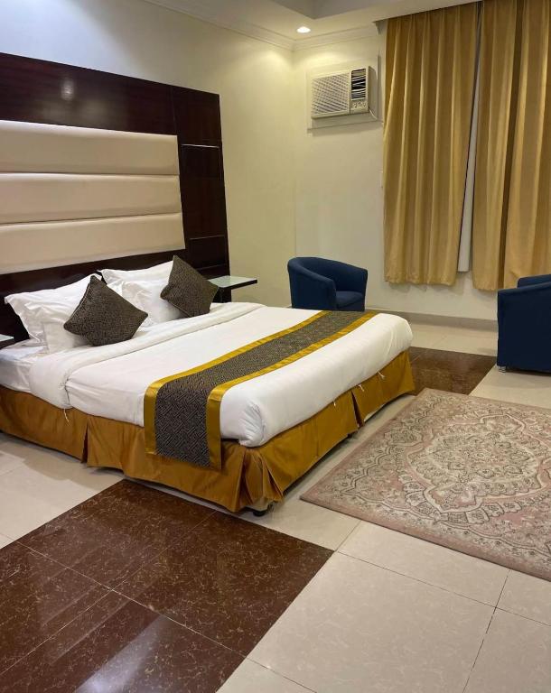 a bedroom with a large bed and two blue chairs at جميــرا لاين in Abha