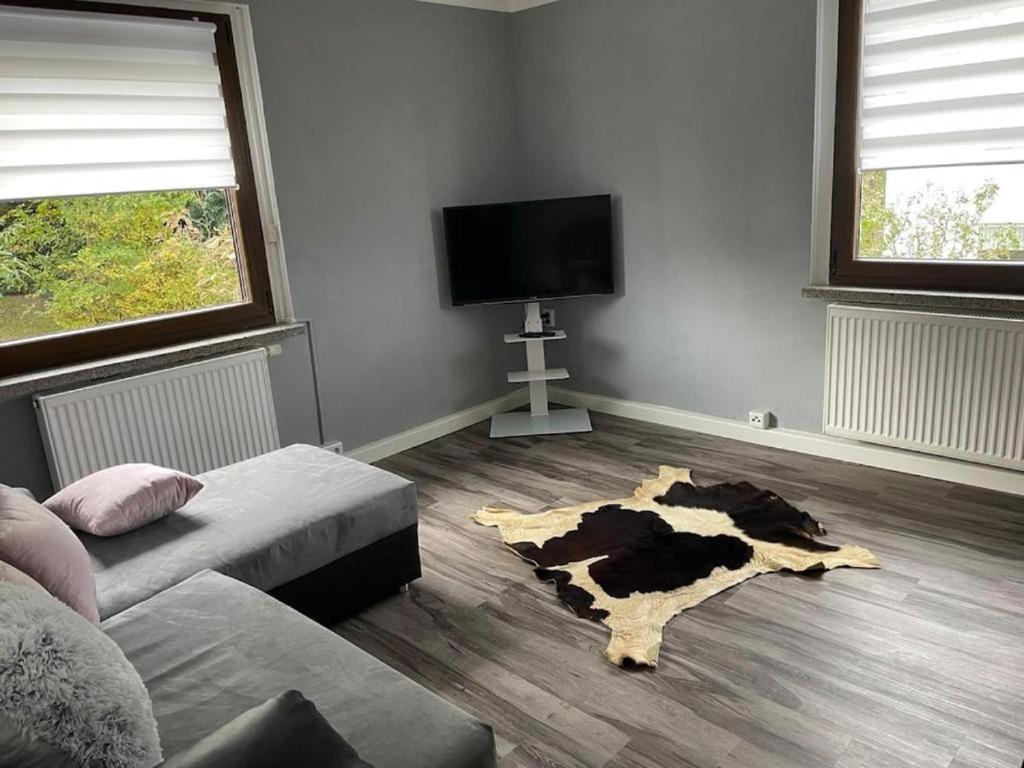 a living room with a cow rug on the floor at Mila's Fewo in Stollberg