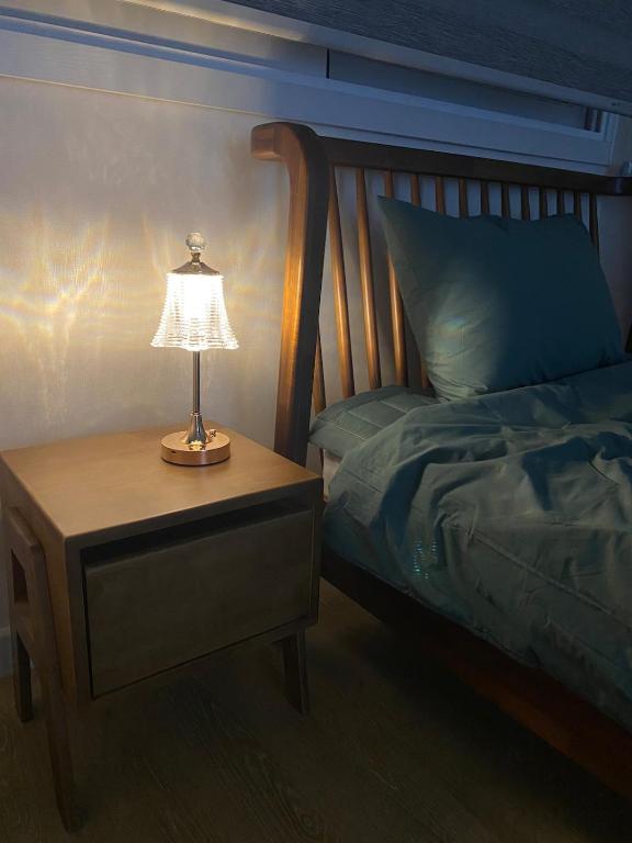 a lamp on a night stand next to a bed at 하우스 The 쉼 in Suwon