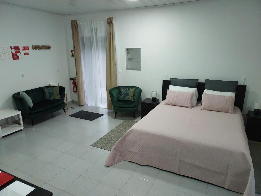 a bedroom with a large bed and two chairs at Retiro das Camélias 3 in Lajes das Flores