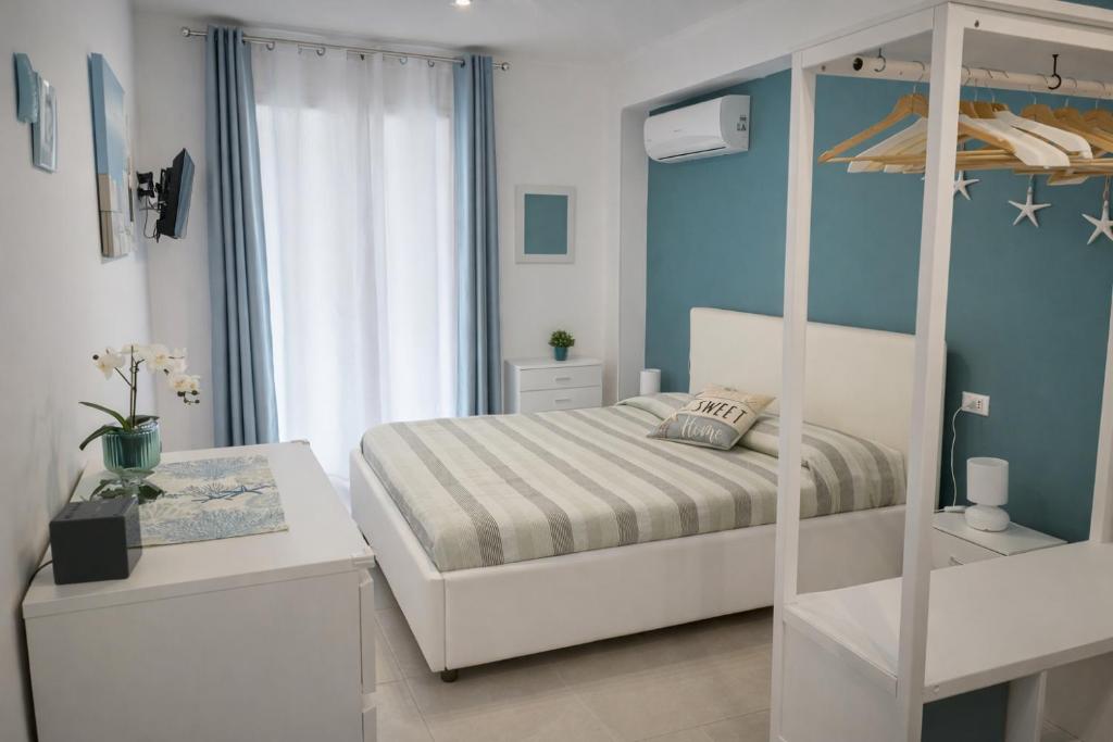a bedroom with a white bed and blue walls at Casa Ventitré in Balestrate
