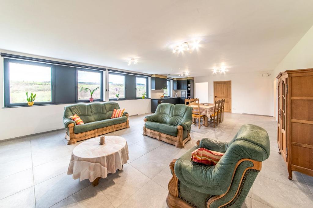 ein Wohnzimmer mit Sofas, Sesseln und einem Tisch in der Unterkunft Le Milan in Nassogne