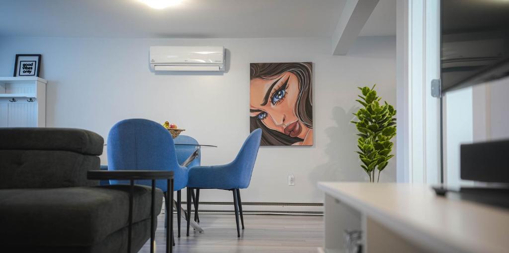a living room with blue chairs and a painting on the wall at Warm and Welcoming Basement in Dieppe