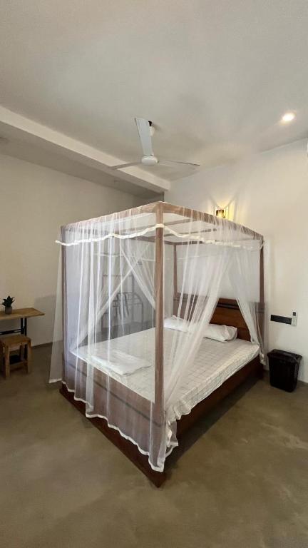 a bedroom with a canopy bed with white curtains at HideWay Guest House Midigama in Midigama East