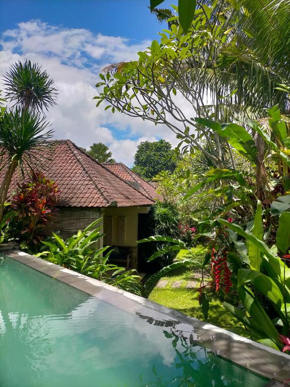 a house with a swimming pool in a garden at Sang Fajar Ubud in Ubud
