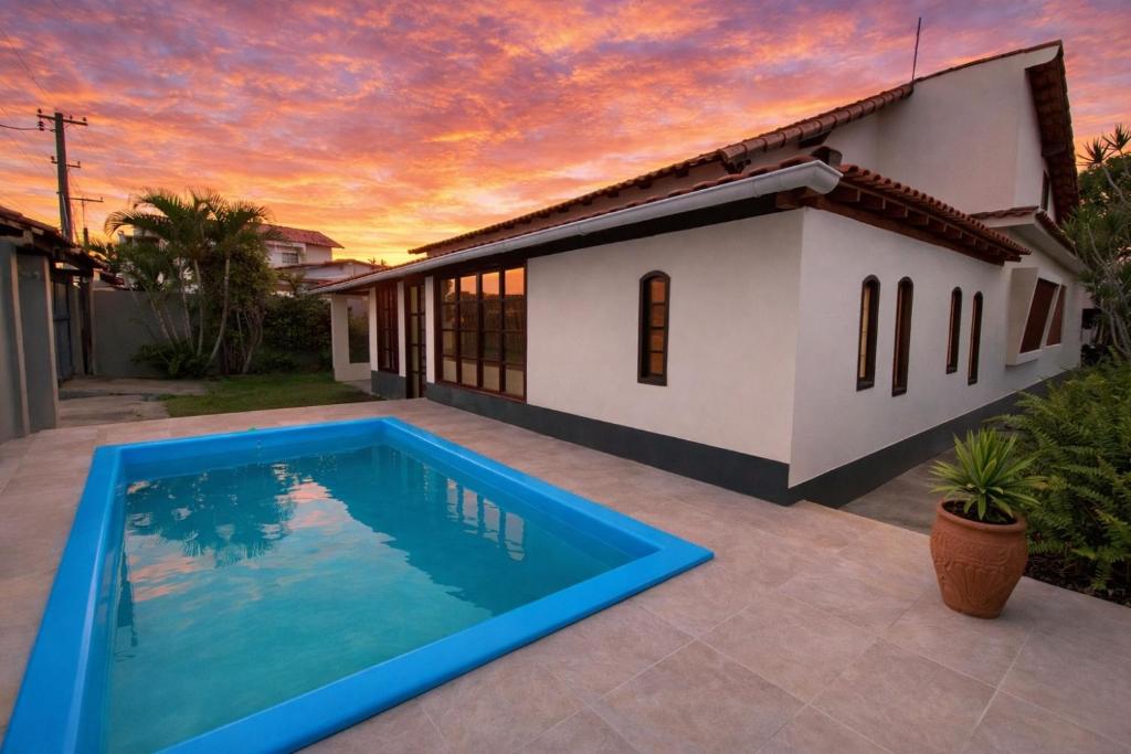 a villa with a swimming pool in front of a house at Meu Point Gravatá 1 - Refúgio Familiar a 100 Metros do Mar in Saquarema