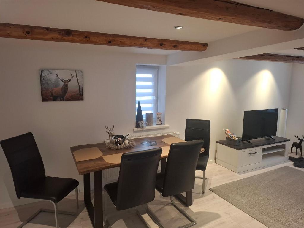 a dining room with a table and chairs and a television at Ferienwohnung Alte Glaserei in Ilsenburg