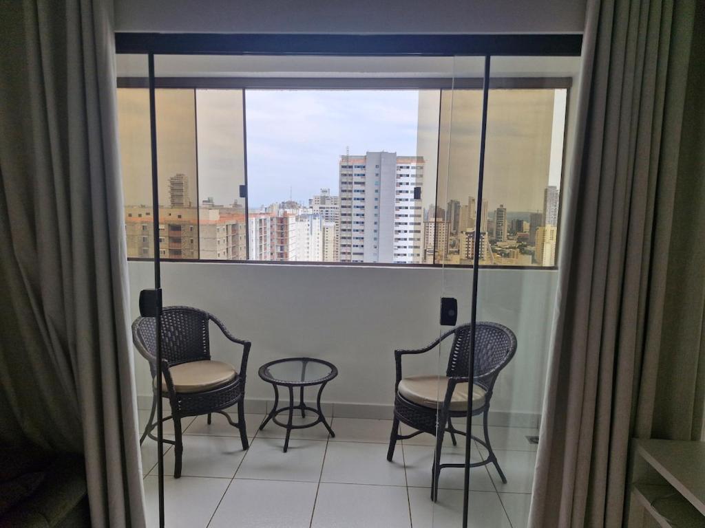 a balcony with chairs and a table in front of a window at Flat com 1 quarto e sala in Goiânia