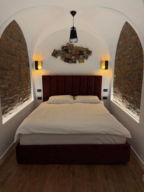 a bedroom with a bed and two arched windows at RotHaus Old Town Sibiu in Sibiu