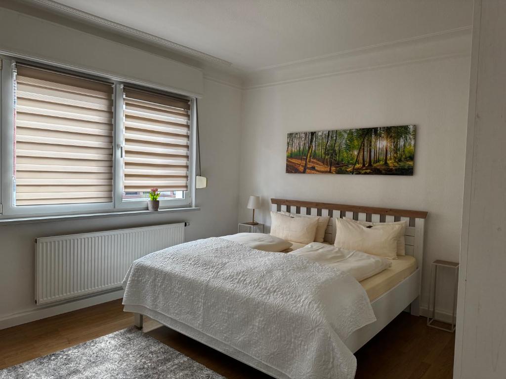 a white bedroom with a bed and two windows at Ferienwohnung Chiara in Mettlach