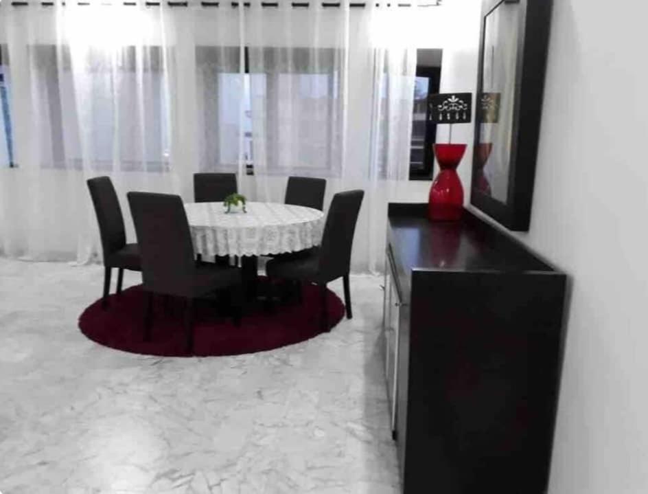 a dining room with a table and chairs and a red vase at Grand et chic appartement in Dakar