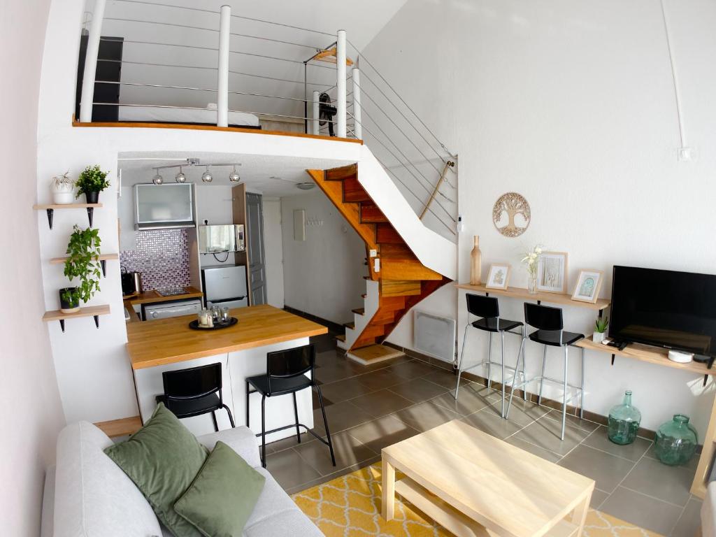 a living room with a staircase and a table at L'Ecrin Duplex Piscine Proche Plage Palavas in Palavas-les-Flots
