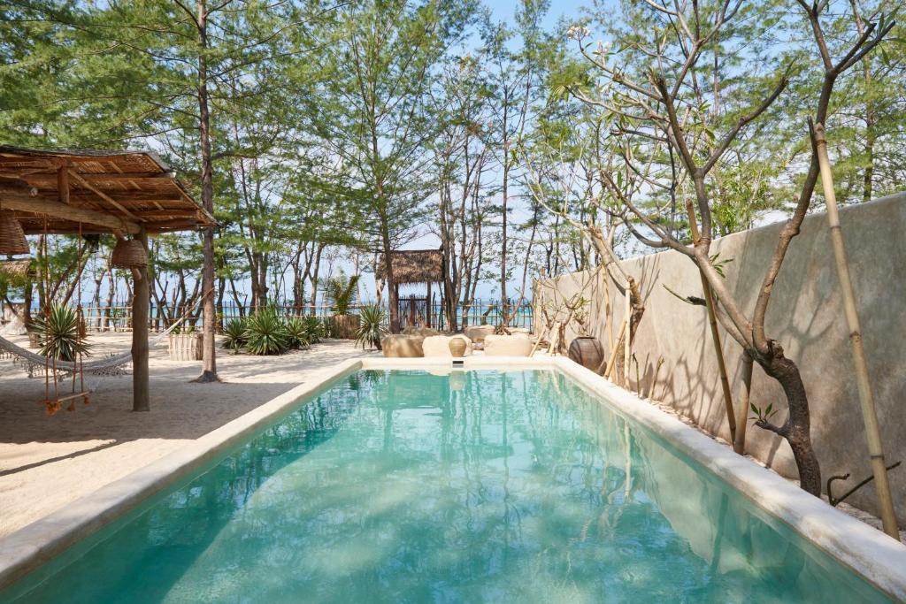 a swimming pool in a yard with trees at The Island Houses Gili Meno in Gili Meno