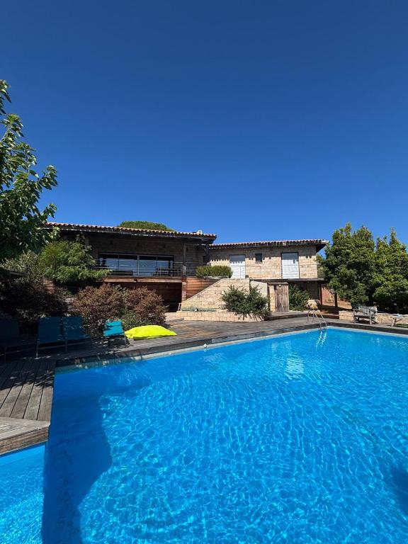 a large blue swimming pool in front of a house at VILLA Cala D'orzu in Coti-Chiavari