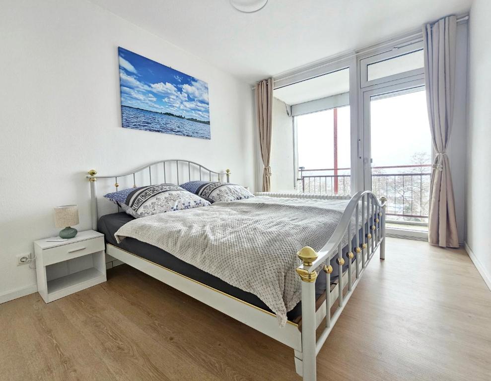 a bedroom with a bed and a large window at Ferienwohnung Sunset - Traumhafter Seeblick & Sauna in Steinhude in Wunstorf