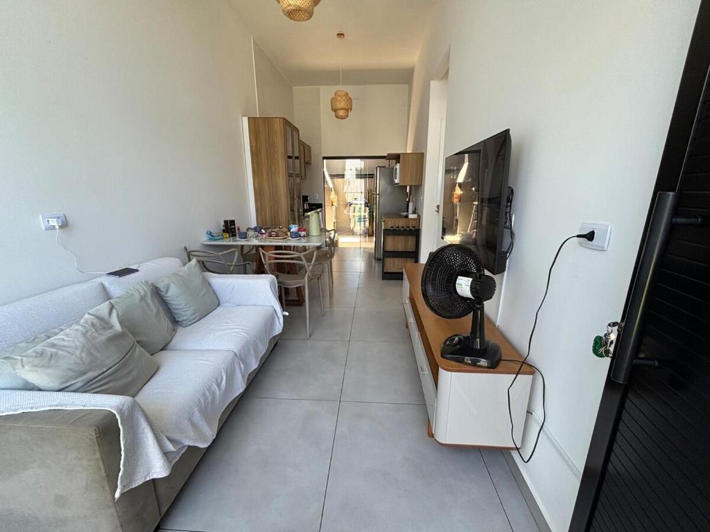 a living room with a white couch and a kitchen at Beach house in Matinhos in Matinhos