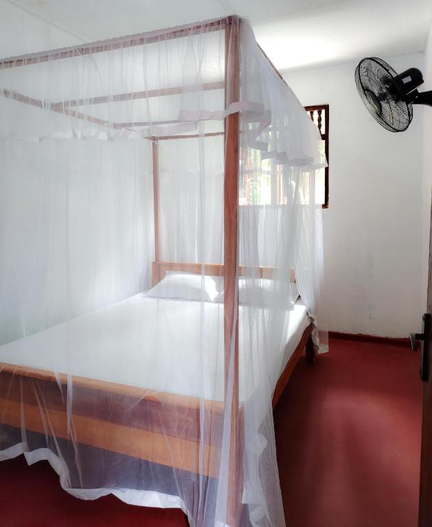 a bedroom with a white bed with a canopy at Indrasiri Villa Midigama in Kumbalgama