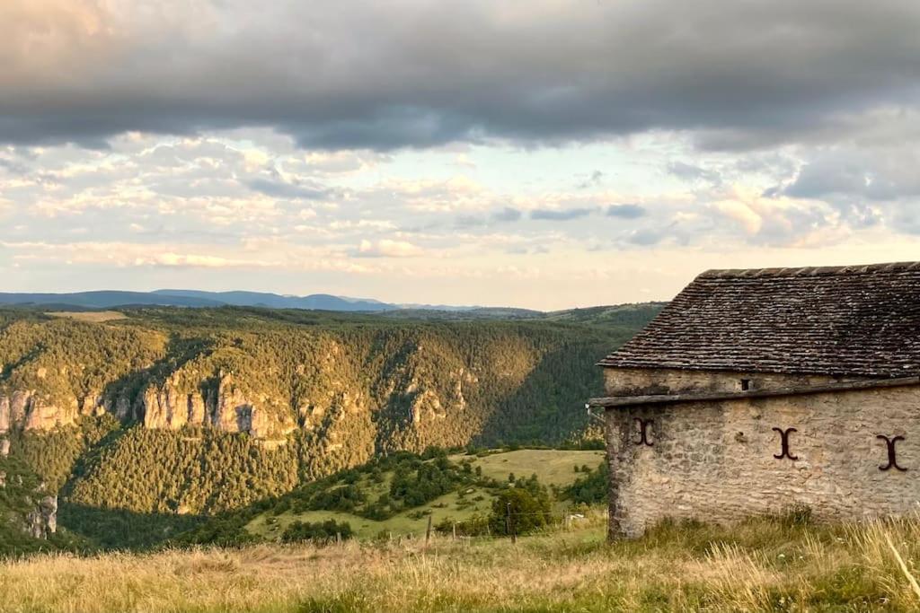an old building on a hill with mountains in the background at Cévennes et Causse Mejean in Dargilan