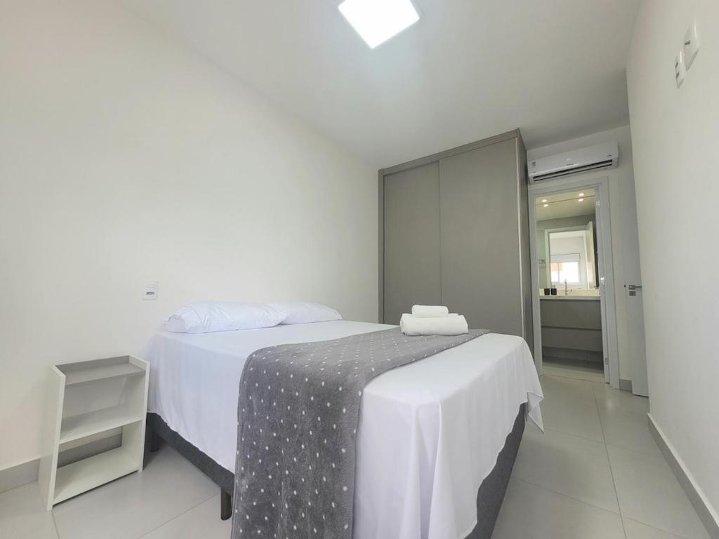a white bedroom with a bed and a mirror at Lavit 92 - Conforto, estilo e lazer com piscina e academia in Bauru