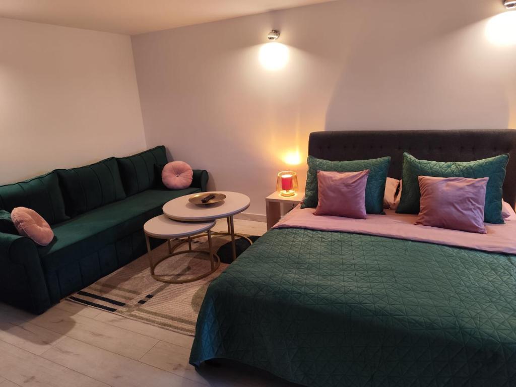 a living room with a green bed and a couch at Pokoje Koral in Mikołajki