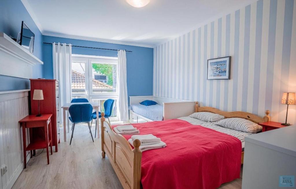 a bedroom with a red bed and a desk and a window at Willa Anna in Jastarnia