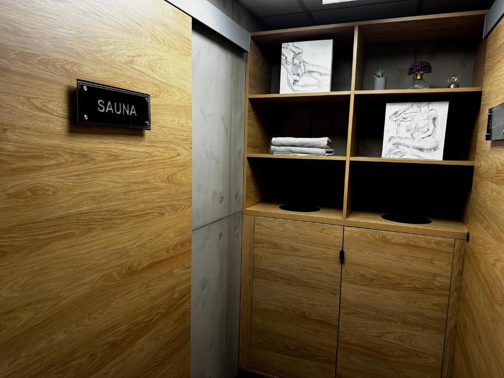 Wood-paneled spa corridor with 'SAUNA' sign and cubby shelving holding folded towels and artwork.