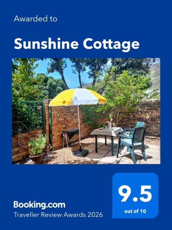 a yellow and white umbrella and a table and a chair at Sunshine Cottage in Fish Hoek