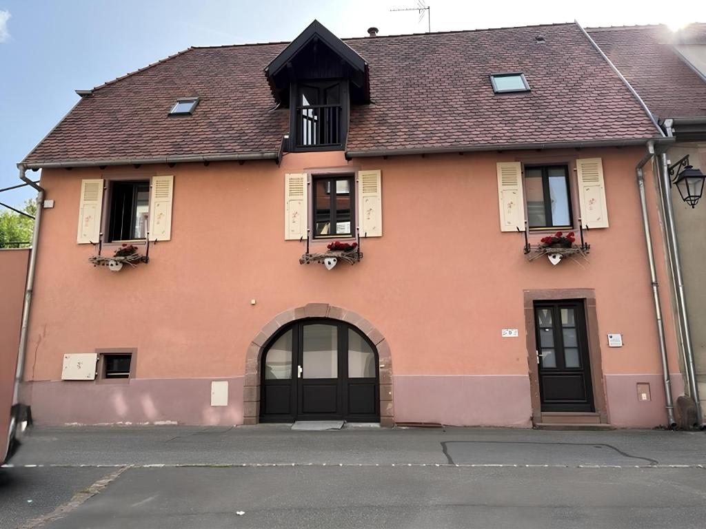 a pink house with a brown roof at Chambre d'hôte chez Hélène in Kaysersberg