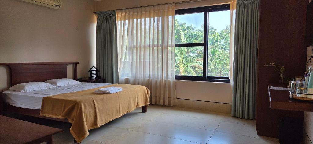 a bedroom with a bed and a large window at Nirmala's Farmhouse - The Blu room in Kuttālam