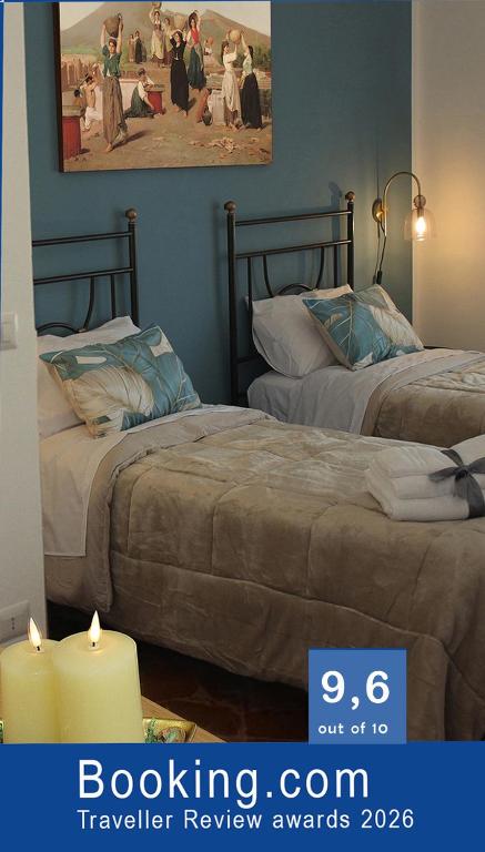 two beds in a room with two candles and a picture at Casa Graziosa in Ercolano